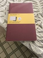 Front view of the set of three maroon Moleskine squared journals in original packaging showing the brand label and details.