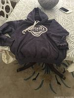 Full view of purple Muskoka Bearwear hoodie sweatshirt laid out on table, showing front logo and drawstring hood.