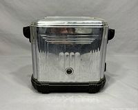 Front view of the vintage Sunbeam electric toaster showing metal body with Art Deco grooved design and central knob.