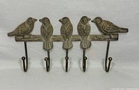 Full view showing all five birds and five hooks, mounted on a branch-shaped base.