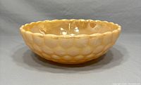 Vintage Fire King Peach Lustre bowl showing side profile with dimpled exterior and scalloped rim.
