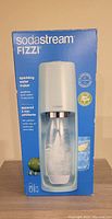 Box image of SodaStream Fizzi sparkling water maker showing model and features on the front.
