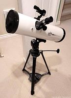 Full view of white EduScience Astro Nova HD 1000 refractor telescope mounted on black adjustable tripod.