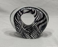 Front view of art glass sculpture showing black and white swirling pattern inside clear glass with hollow oval center.