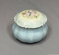 Front angled view of the vintage Limoges trinket box showing floral lid and blue base.