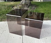 Two vintage MCM acrylic nesting tables outdoors on concrete with grass background showing amethyst tint, size difference, and condition.