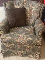 Armchair with floral upholstery and cushion resting on the seat, showing full front view.