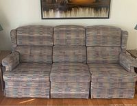 Frontal view of three-seat couch with striped upholstery and padded armrests