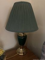 Table lamp with medium green pleated fabric shade and polished brass base with green ceramic body