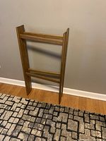 Solid wood quilt rack photographed standing upright against a wall, displaying the three horizontal bars and natural wood finish.