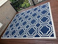 Full view of navy and cream area rug on wooden floor showing overall pattern and size.