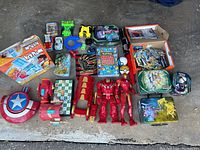 Wide view of all toys in the box spread out showing various items including games, action figures, and cards.
