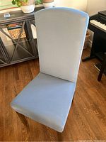 Front view of a blue chair cover fitted on a dining chair showing the smooth texture of the fabric and the snug fit over the backrest and seat.