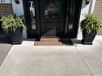Two large black outdoor planters placed at the entrance showing proportions and placement with ferns inside (not included).