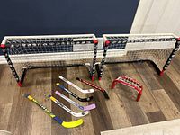 Mini hockey sticks laid out in front of two mini hockey goal nets and one small red shooting net.