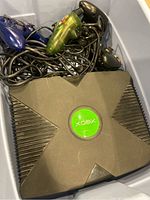 Original Xbox console with wired controllers piled on top in plastic container