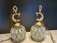 Pair of vintage 1950s Hollywood Regency hanging swag lamps with cast metal koi fish and glass globes shown side by side.