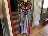 Full front view of the Joseph and the Amazing Technicolor Dreamcoat costume coat on a mannequin showing the colorful applique bodice and silver base fabric with cape panels.
