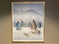 Frontal photo of the full oil painting showing junk boats on water with cityscape and mountains in background, framed in gold.