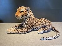 Side view of the plush leopard showing the detailed spotted fur pattern, tail, and profile of the face.