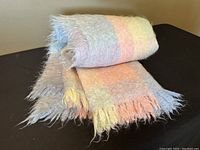 Rolled pastel rainbow mohair wool blanket showing soft texture and fringed ends.