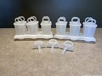 Two trays each holding six vintage Tupperware popsicle molds with three extra tops in front.