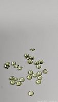 Multiple small round-cut natural peridot gemstones on a neutral background showing size, cut, clarity and color.