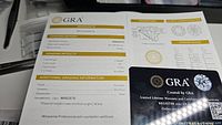 Close-up photo of 2 Ct GRA grading report showing moissanite certification details including color D, clarity VVS1, cut grade excellent