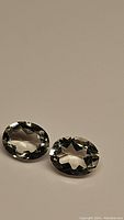 Pair of oval cut natural green amethyst gemstones on neutral background showing their color and cut.