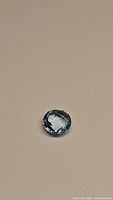 Top view of the round faceted natural Swiss blue topaz gemstone on a neutral background.