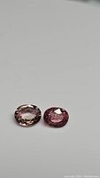 Pair of natural untreated tourmalines, one light pink champagne and one vibrant pink, displayed on a neutral background.