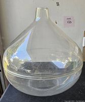 Clear acrylic bulbous round terrarium with a narrow neck on a black surface showing its overall shape and transparency.