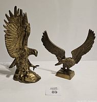 Photo showing both brass eagle sculptures side by side on a white background.