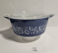 Side angled view of the blue Colonial Mist Pyrex serving bowl with clear glass lid showing floral patterns and handles.