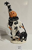 Front view of the Dee Faust-Harvey Kenley's Kitty Halloween statue showing pumpkin-headed character in white spider-decorated costume holding black cat on leash.