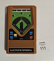 Front view of the vintage electronic baseball handheld game, showing the baseball field graphic and control buttons.
