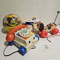 Collection of four Fisher-Price toys including the phone, pull dog, carousel dome, and cash register