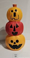 Photo of the stacked pumpkins in daylight showing the colors, facial features on each pumpkin, and overall shape.