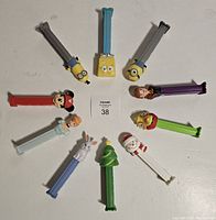 Top view of all 10 PEZ dispensers arranged in a circle showing character heads and varying colored stems.