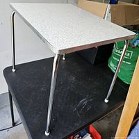 Image showing the top surface of the small table with a white speckled formica top and tubular chrome legs.