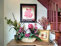 Wide shot of the table showing all included items: floral arrangements, Buddha figurine, and framed art pieces placed under stairs