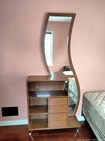Full view showing wooden table unit with curved mirror, three drawers, open shelves, and glass corner shelf on caster wheels.