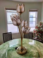 Lotus table lamp with brass-tone base and four lotus flower-shaped frosted glass shades, displayed on a green marble table.
