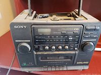 Front view of the Sony CFD-440 boombox showing digital display, radio frequency scale, cassette deck, control knobs and buttons.