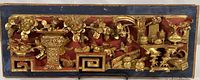 Full frontal view of the antique wooden panel showing entire carved and painted design with gold highlights on red background and a blue border.