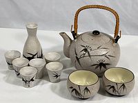 Photo showing the entire tea and sake set with teapot, two teacups, sake vessel, and six sake cups, all decorated with bamboo motif.