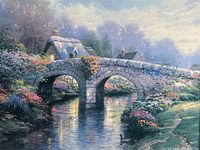 Close view of hand-highlighted canvas print depicting stone bridge over water with floral surroundings in daylight setting.
