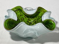 Top and side views of hand formed green and white glass dish with gold bubble flecks inside.