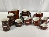 Full set displayed on white surface showing milk pitcher, cappuccino cups and saucers, espresso cups, and additional saucers.