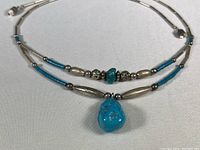 Full view of the silver and turquoise necklace showing the full length with the large turquoise pendant at the center.